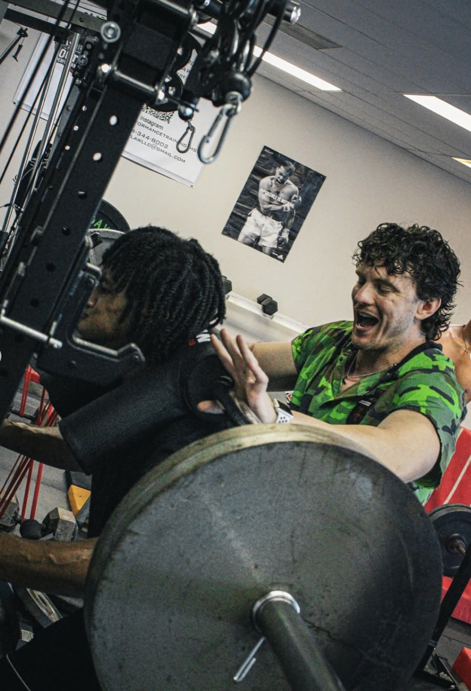 Coach spotting an athlete through a heavy barbell set